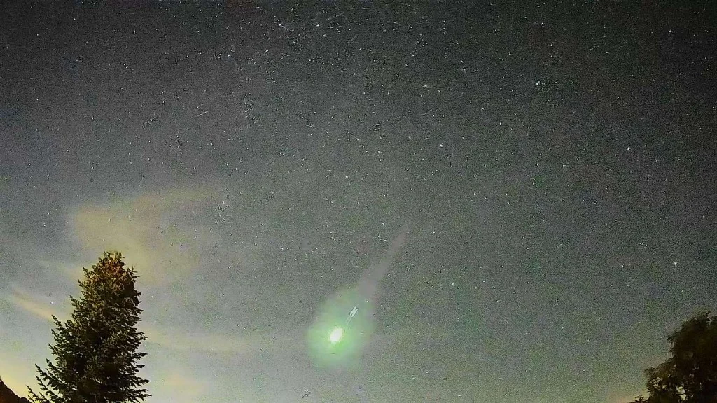 Heller Meteor mit grünlichem Licht am nächtlichen Sternenhimmel